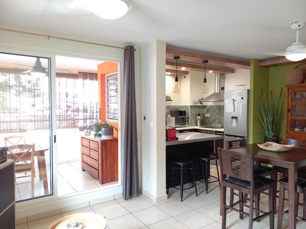 a kitchen with a table and a dining room at Bel Appartement avec terrasse proche des plages in Saint-Gilles les Bains