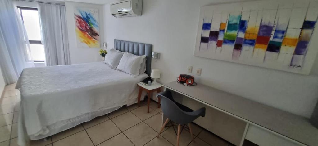 Dormitorio con cama, escritorio y algunas pinturas en Flat Na Praia Mucuripe, en Fortaleza