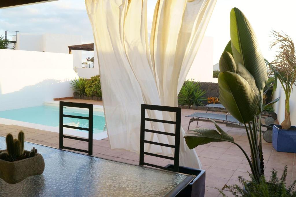 patio ze stołem i krzesłami oraz basenem w obiekcie Villa Tabaiba Playa Blanca Lanzarote w mieście Playa Blanca