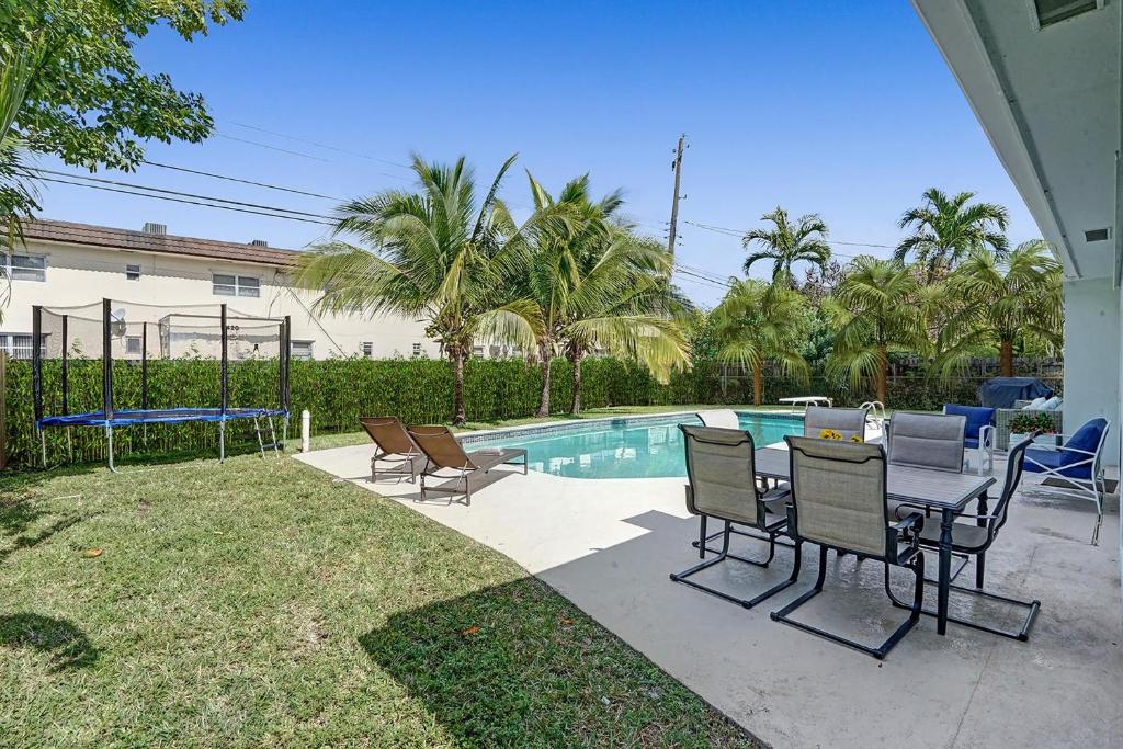 a patio with a table and chairs next to a pool at Huge Villa With Heated Pool, Trampoline Bbq in Miami Gardens