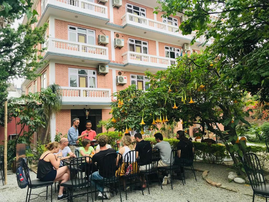un grupo de personas sentadas en una mesa frente a un edificio en Cloud 9 Garden en Katmandú