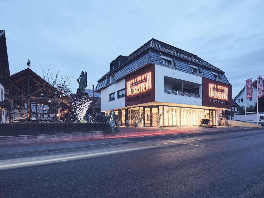 ein Gebäude mit Neonschildern an der Straßenseite in der Unterkunft Hotel Hornstein - Weingut, Vinothek & Gastronomie in Nonnenhorn