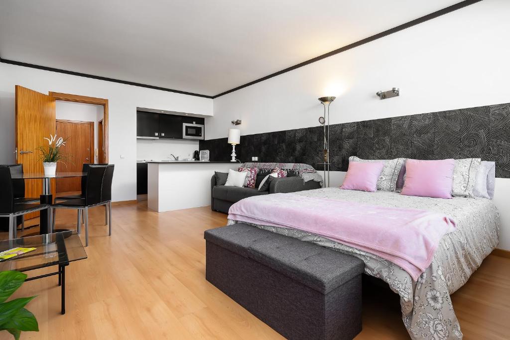 a bedroom with a large bed and a living room at Apartamento Portugal in Quarteira