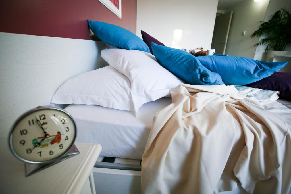 a bed with pillows and a clock on a table at Hotel Cicò in Torre Santa Sabina