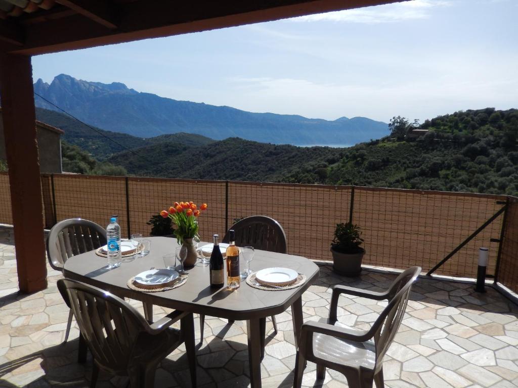 - une table sur une terrasse avec vue sur les montagnes dans l'établissement Maison de village située dans le magnifique Golfe de Porto, à Osani
