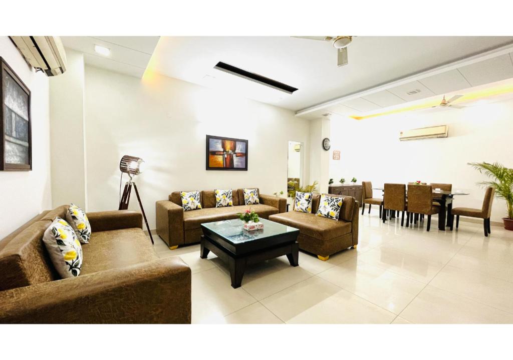 Una sala de estar con sofás y una mesa y sillas. en BluO 2BHK - Greater Kailash Lift Balcony Parking, en Nueva Delhi
