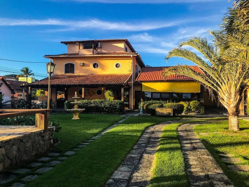 a house with a palm tree in the yard at Pousada Estalage in Cabo Frio