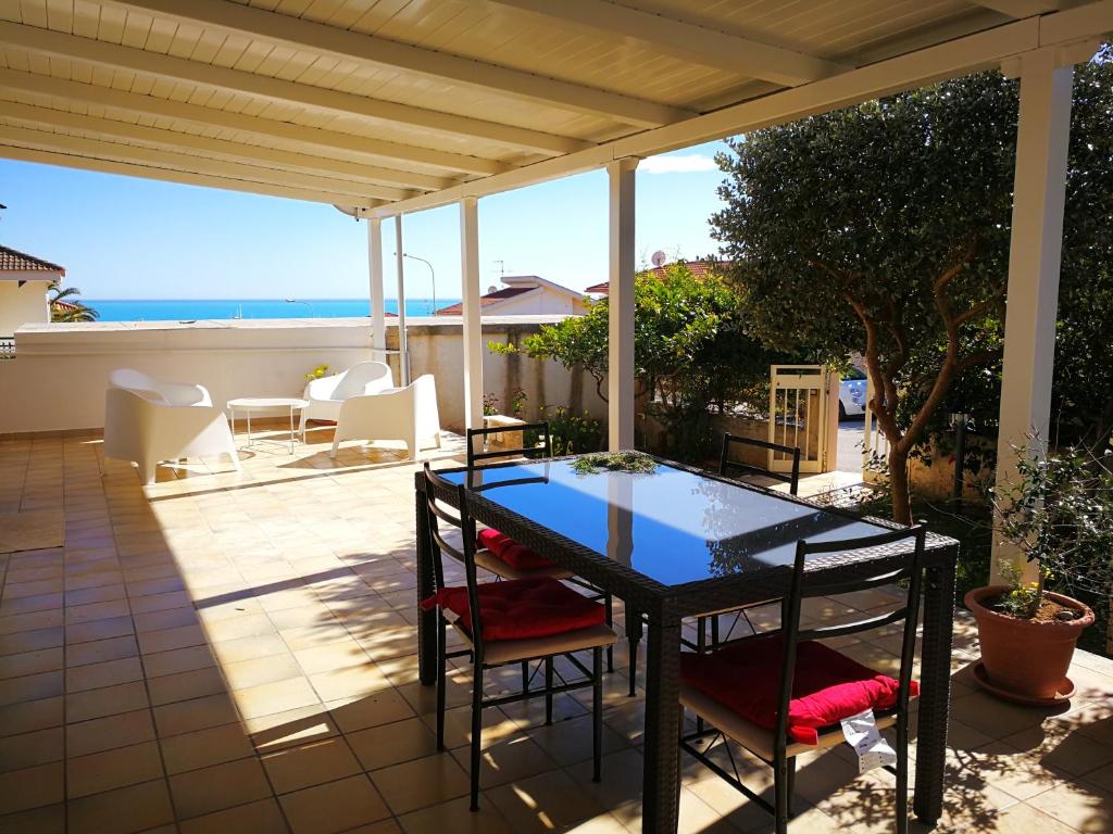 un patio con tavolo, sedie e vista sull'oceano di La casa di Lillo a Marina di Ragusa