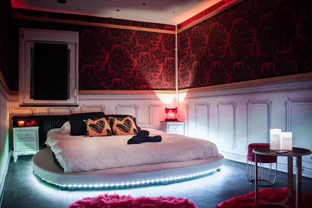 - une chambre avec un grand lit et un mur rouge dans l'établissement Bulle d’Amour , une nuit en amoureux, à Thann