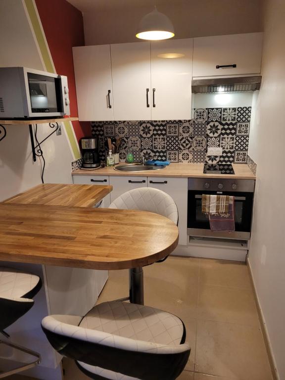 eine Küche mit einem Holztisch und weißen Schränken in der Unterkunft la grange in Coigneux