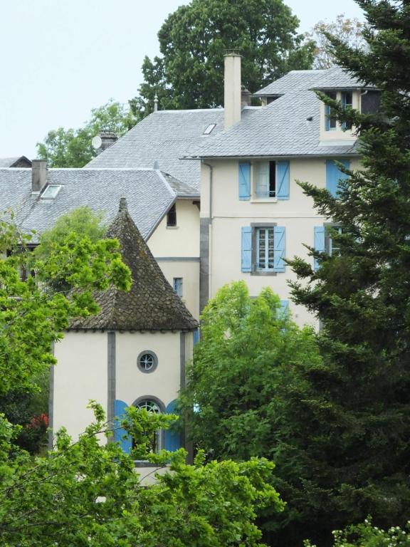a white house with blue windows and trees at LES ANDALOUSES in Avèze