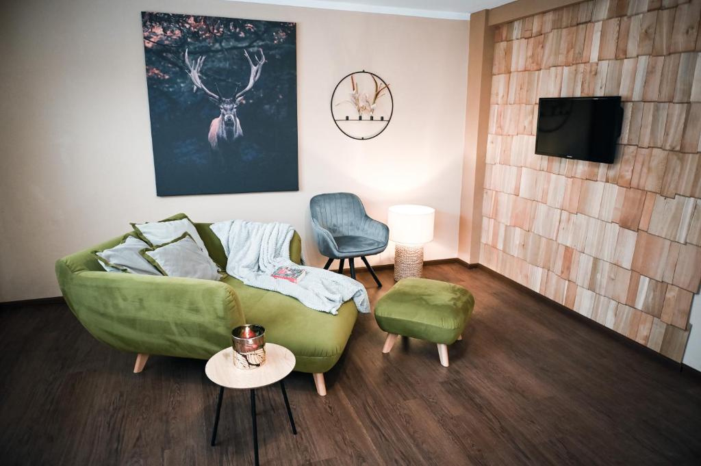 a living room with a green couch and a chair at FeWo Herbst in der Villa Waldrand mit Luxus Bad in Bad Wünnenberg