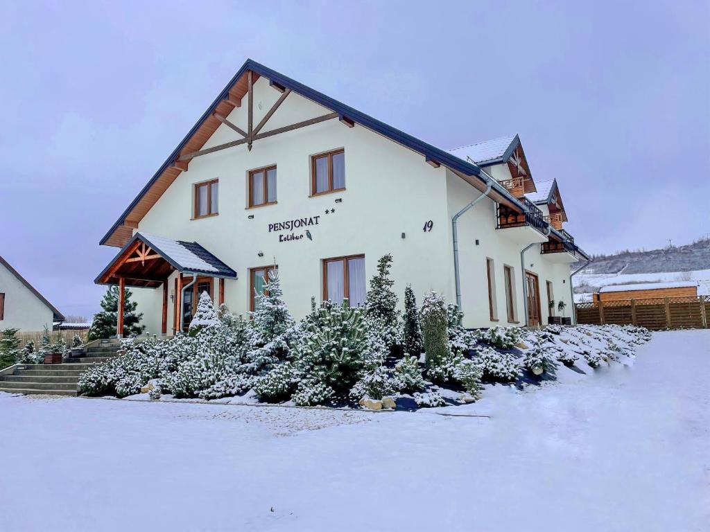 budynek z śniegiem na ziemi przed nim w obiekcie Pensjonat Koliber w mieście Sobków