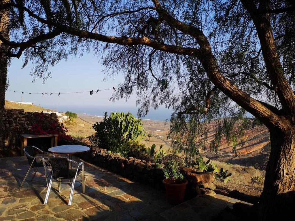 a table and chairs sitting on a patio under a tree at Apartamento Pirul in Haría