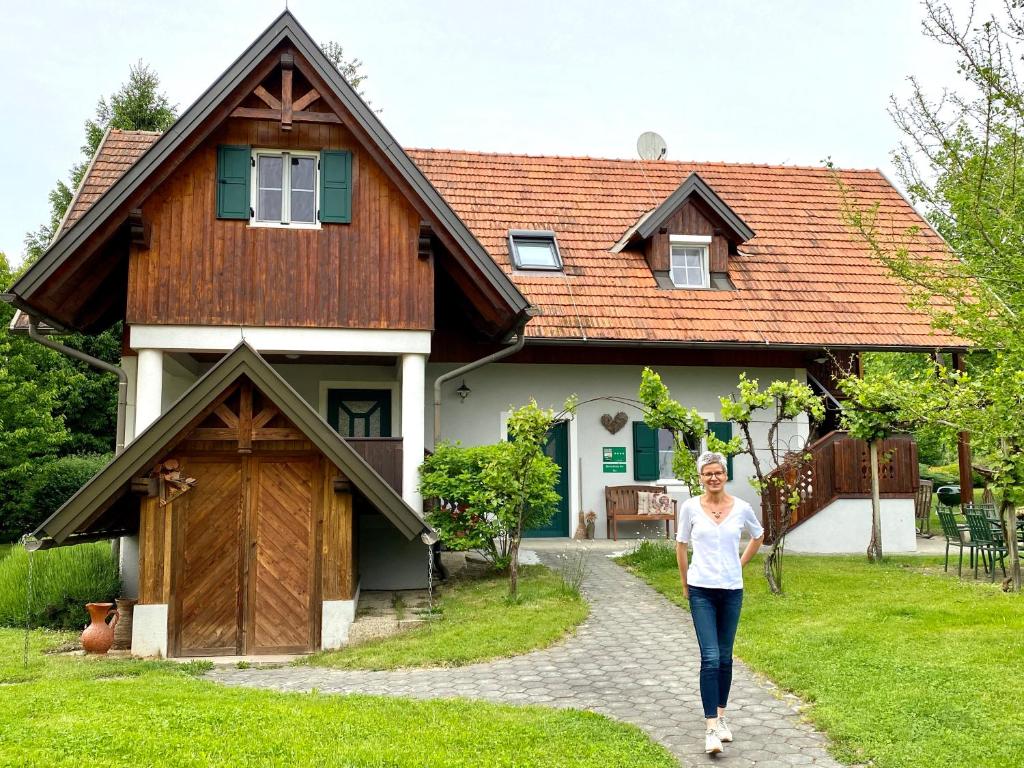 a woman walking in front of a house at Landhaus Bender Ferienwohnung mit Terrasse und Garten in Straden