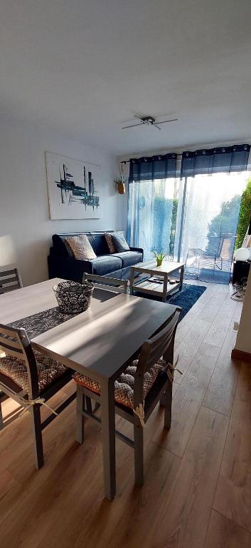 un soggiorno con tavolo e divano di Cosy studio le Garden ensoleillé a Cabourg