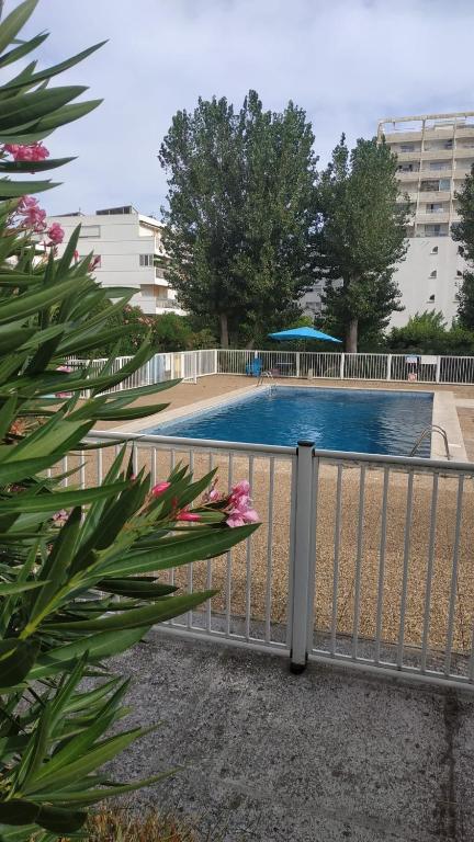 une clôture en face d'une piscine dans l'établissement DOUKA APPART T2 WIFI CLIM PISCINE en saison - CENTRE PROCHE PLAGE-PORT - La Grande Motte, à La Grande Motte