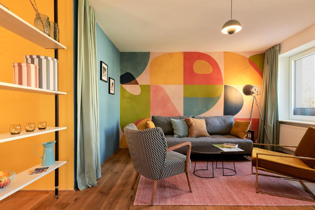 a living room with a couch and a colorful wall at Rotes Haus Bregenz Pop-Up Wohnung in Bregenz