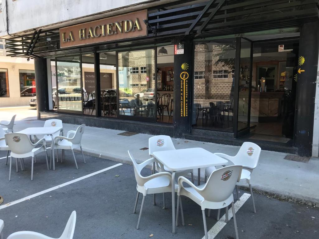 un grupo de mesas y sillas frente a un restaurante en PENSIÓN LA HACIENDA, en Padrón