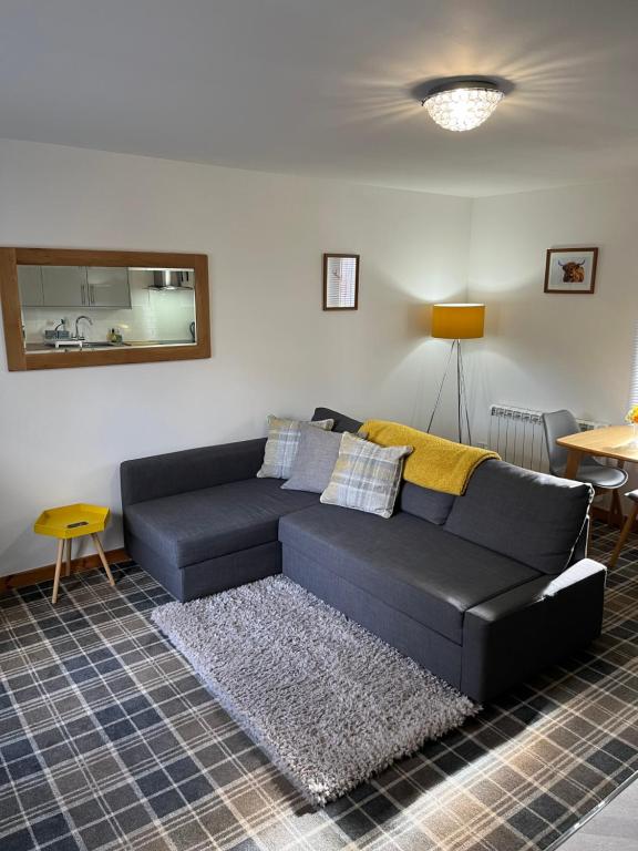 a black couch in a living room with a rug at Tigh Stobban Apartment 1 in Fort William