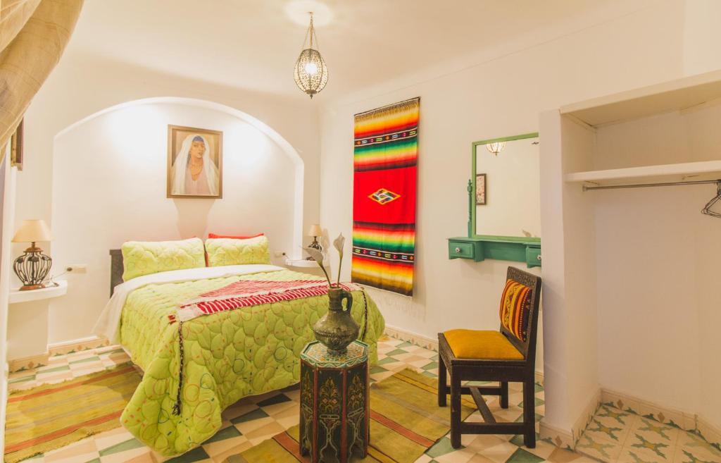 een slaapkamer met een bed en een stoel bij Riad Azul in Essaouira