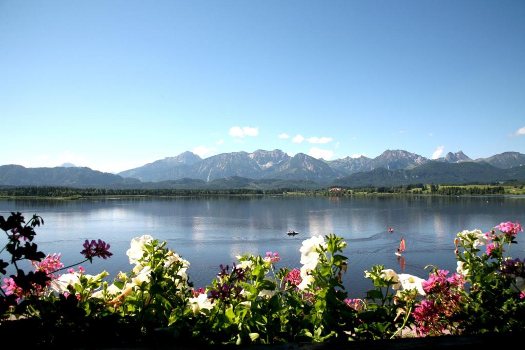 einen Blick auf einen See mit Bergen im Hintergrund in der Unterkunft Seehotel Hartung & Ferienappartements in Füssen