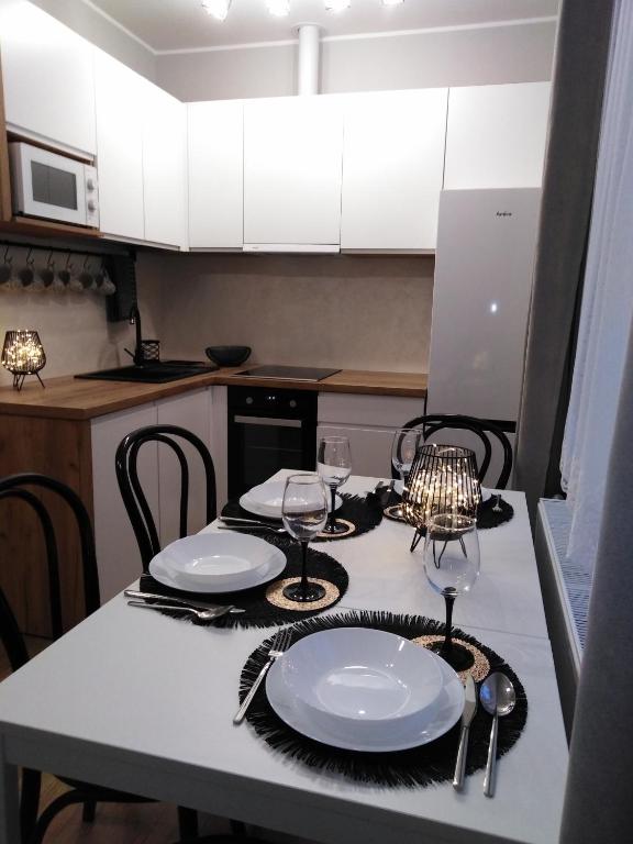 a kitchen with a table with plates and wine glasses at Apartament JOANNA in Sanok