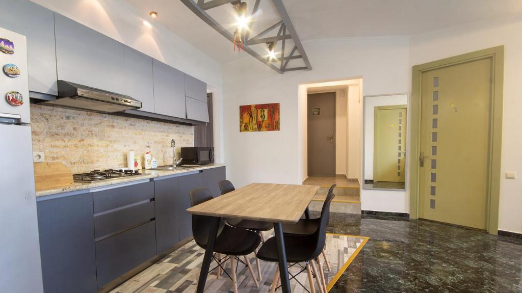une cuisine avec une table en bois et quelques placards bleus dans l'établissement 4 Bedroom Apartment on Liberty Square, à Tbilissi
