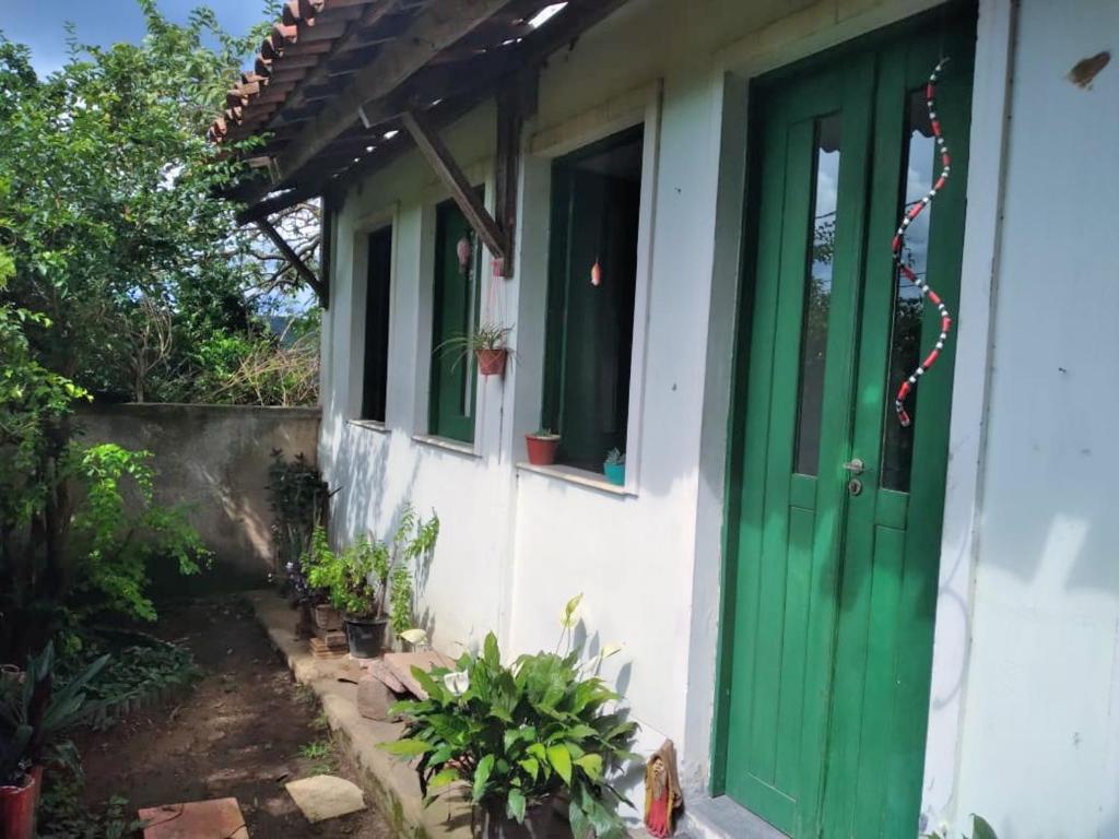 uma porta verde numa casa branca com plantas em Casa Relva em Lençóis