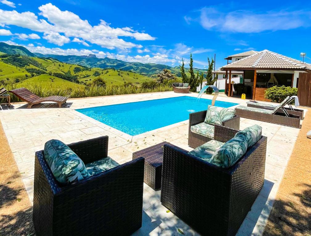 una piscina con 2 sillas de mimbre frente a una casa en Pousada Viver a Pedra en Gonçalves