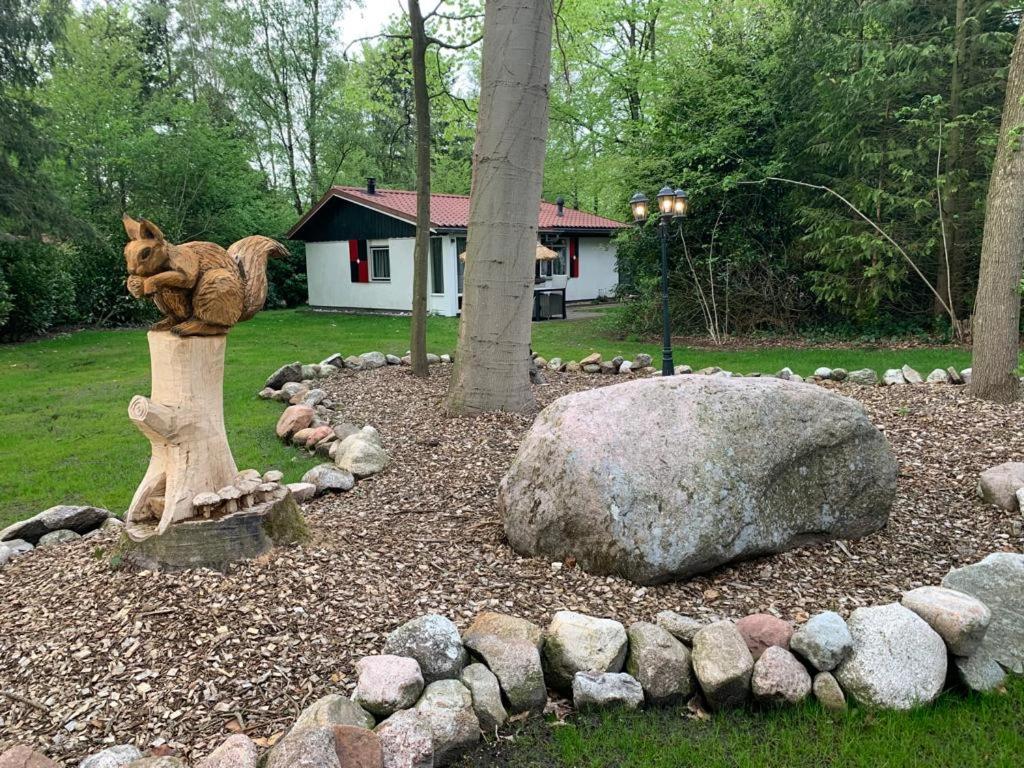 einen Garten mit einer Statue einer Katze auf einem Felsen in der Unterkunft Huisje 96 in Exloo