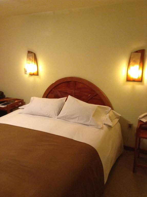 a bedroom with a large bed with two lights on the wall at Royal Inn Hotel Juliaca in Juliaca