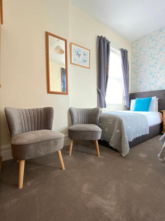 a bedroom with a bed and a pair of chairs at Coastal Waters (Hotel Barton) in Torquay