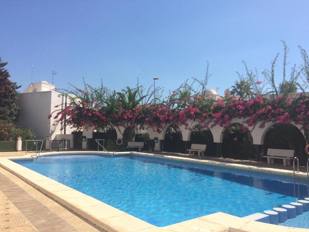 a swimming pool with pink flowers on a building at Puerto de Mazarrón - Large 2 or 3 Bedroom House with Roof Terrace and Wonderful Sea Views in Puerto de Mazarrón