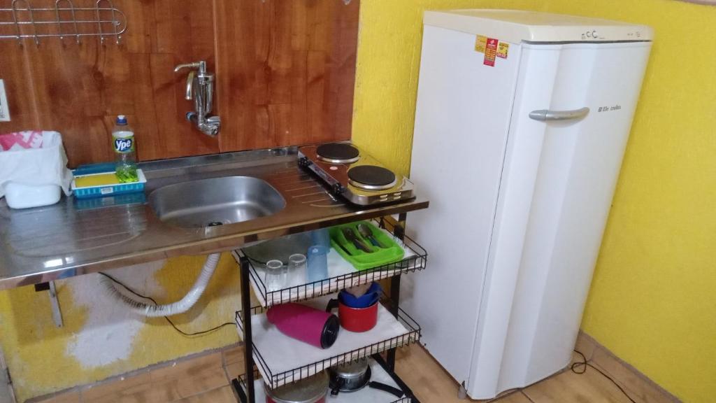 una pequeña cocina con fregadero y nevera. en Quitinete Expominas Suite e Ar, en Belo Horizonte