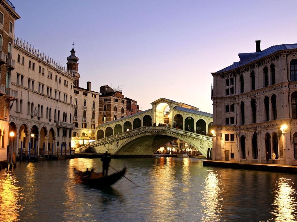 un pont sur une rivière avec un bateau dans l'eau dans l'établissement Ai Boteri, à Venise