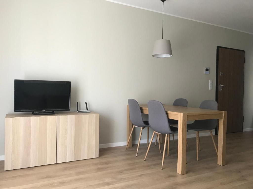 a dining room with a table and chairs and a television at Apartament AG5 in Gdańsk