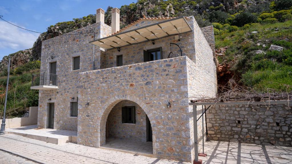 a stone building with an archway on a hill at Alexandra's House in Limeni
