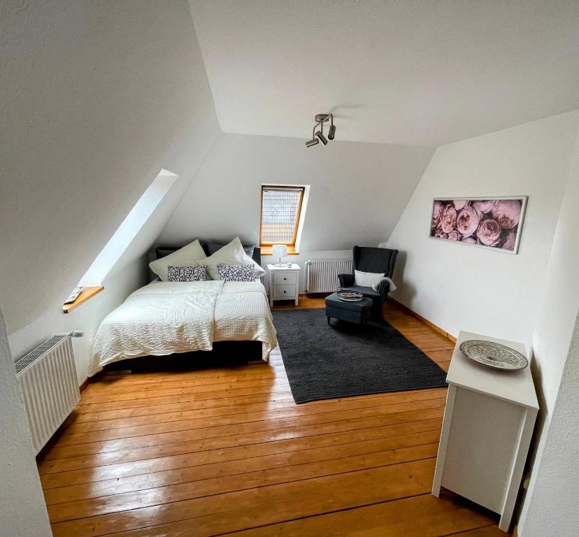 1 dormitorio con 1 cama y 1 silla en el ático en *To hus* Wohnung am Rande von Jever, en Jever