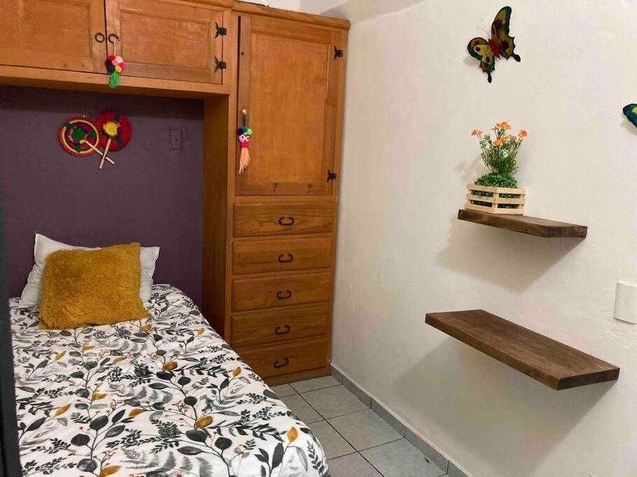 ein Schlafzimmer mit einem Bett und einer Holzkommode mit Blumenarrangement in der Unterkunft Acogedora habitación privada en Jalatlaco in Oaxaca de Juárez