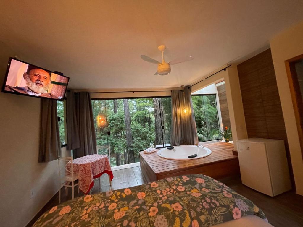 a bedroom with a bed and a bathroom with a sink at Pousada Vale das Orquídeas in Lavrinhas