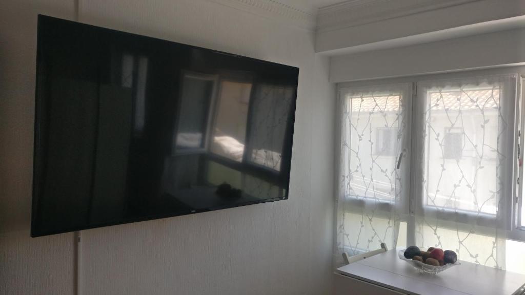 a flat screen tv hanging on a wall next to a window at Laredo primera línea de playa,zona puerto deportivo in Laredo