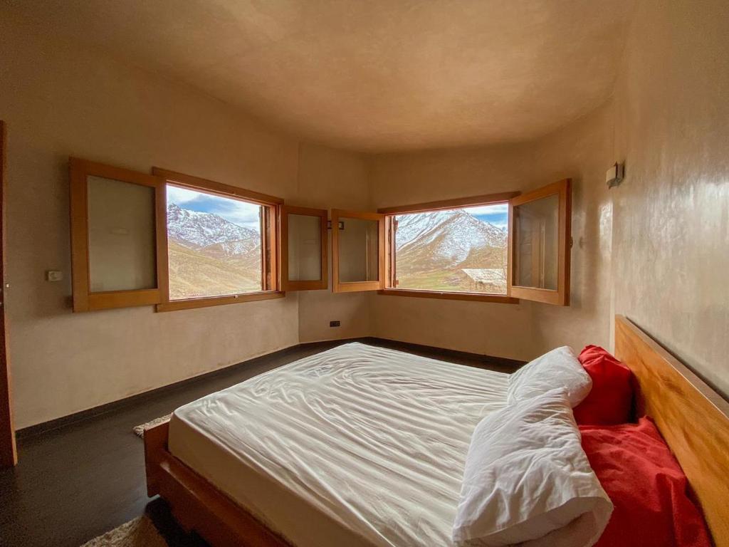 a small bedroom with a bed and two windows at Chalet Ermitage Oukaimeden in Oukkainrdem