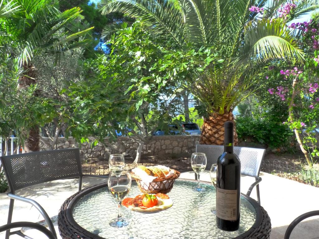 a table with a bottle of wine and a basket of fruit at Apartments Ivanković in Trogir