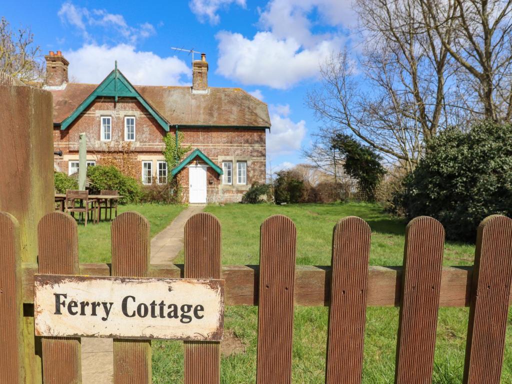 a sign on a fence in front of a farm house at Ferry Cottage in Sudbourne
