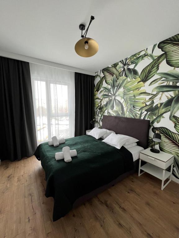 a bedroom with a green bed with a tropical wallpaper at Bielany Apart Joanny obok metra in Warsaw