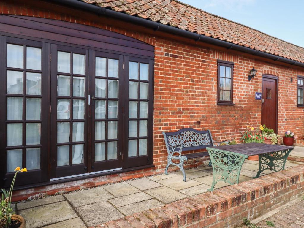 um banco e uma mesa em frente a uma casa de tijolos em Barn Owl Cottage em Little Glenham