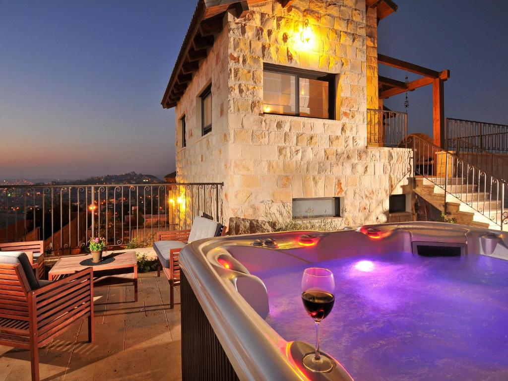 una bañera de hidromasaje con una copa de vino frente a una casa en סחלב פראי Wild Orchid Luxury Suites en Kefar Weradim