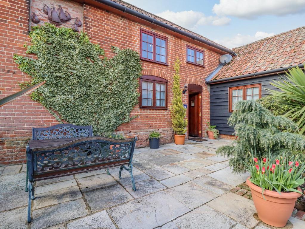 a bench sitting in front of a brick building at Hayloft Cottage in Little Glenham