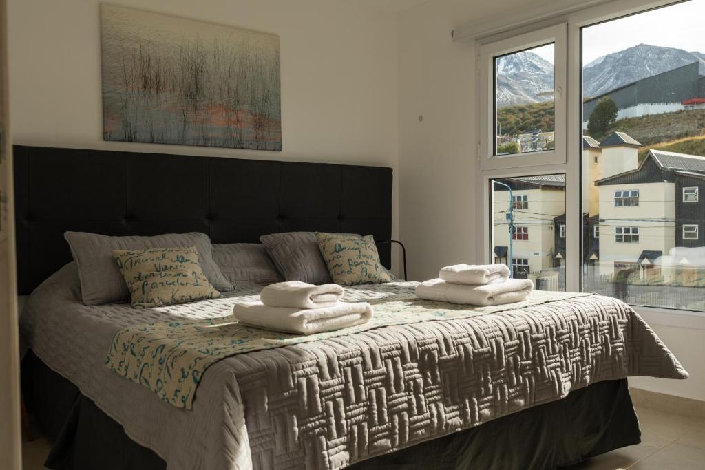 een slaapkamer met een groot bed en 2 handdoeken bij Departamentos La Fe 2 in Ushuaia
